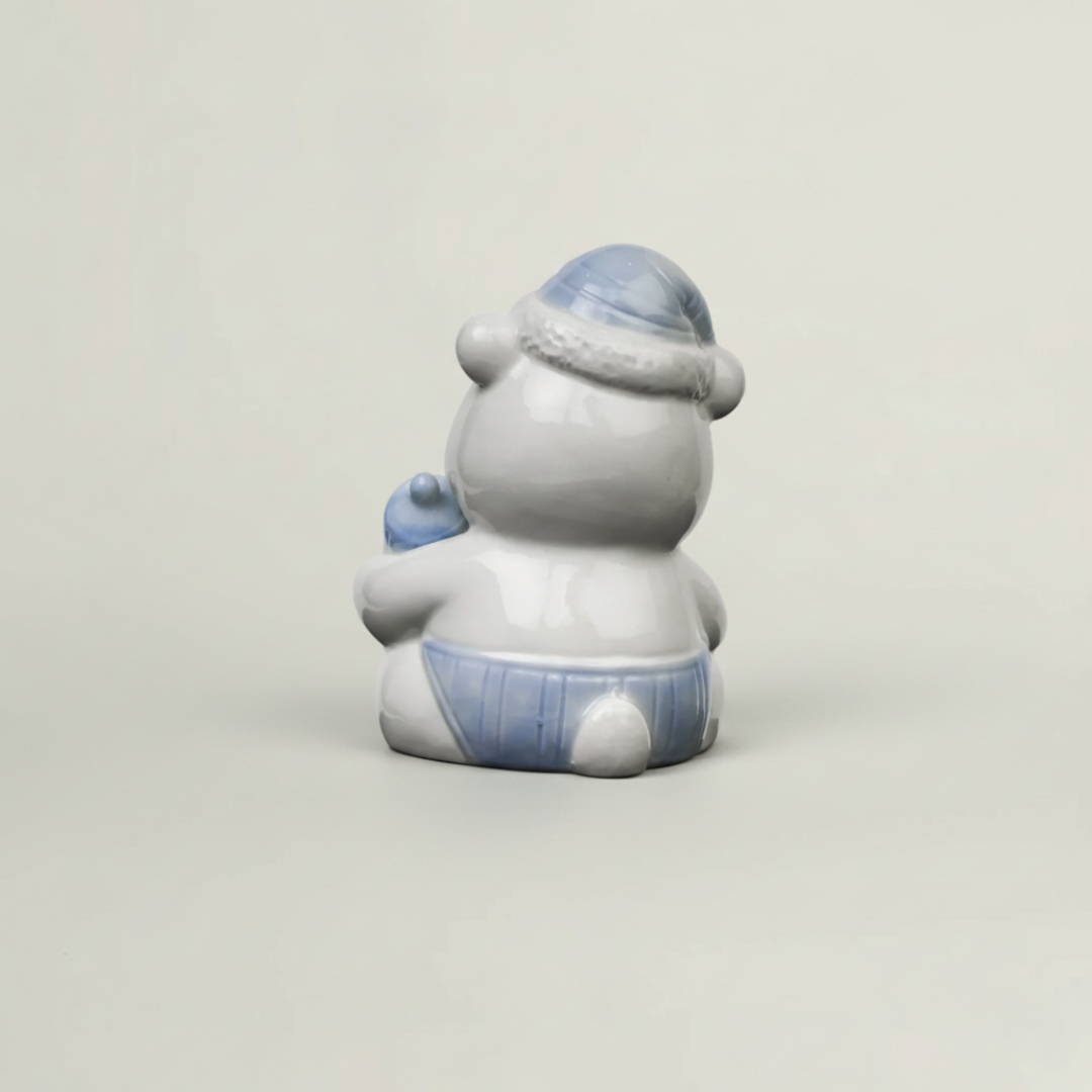 Back view of blue ceramic baby teddy bear figurine with glossy finish, pastel nursery shelf decor and baby keepsake collectible