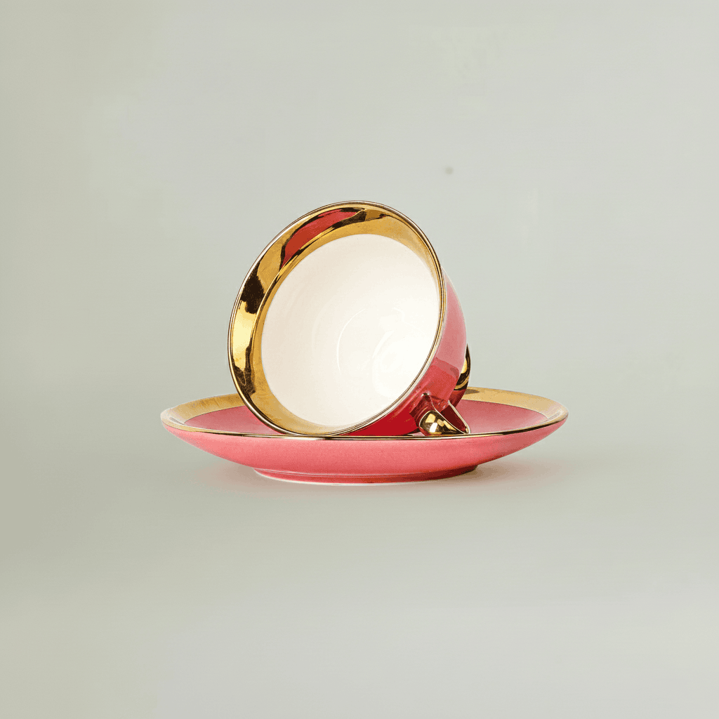 Pink tea cup displayed upside down on saucer with gold rim