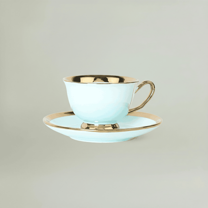 Sky blue ceramic coffee cup and saucer with elegant gold rim detailing, presented in a minimal studio setting.