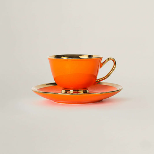 Orange porcelain tea cup and saucer with gold rim by Fleur de Lis