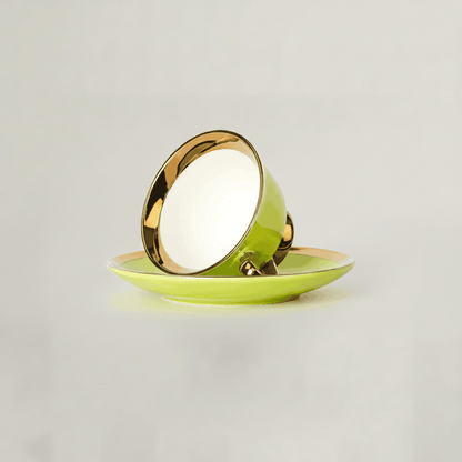 Green tea cup resting on saucer showcasing gold rim finish