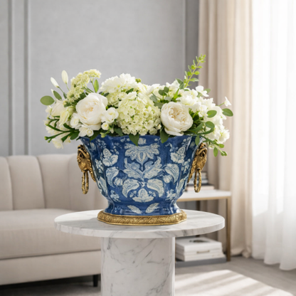 Blue ceramic floral planter with gold detailing, styled with fresh white flowers as a refined centerpiece for luxury interiors.