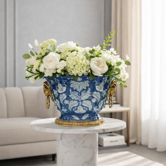 Blue ceramic floral planter with gold detailing, styled with fresh white flowers as a refined centerpiece for luxury interiors.