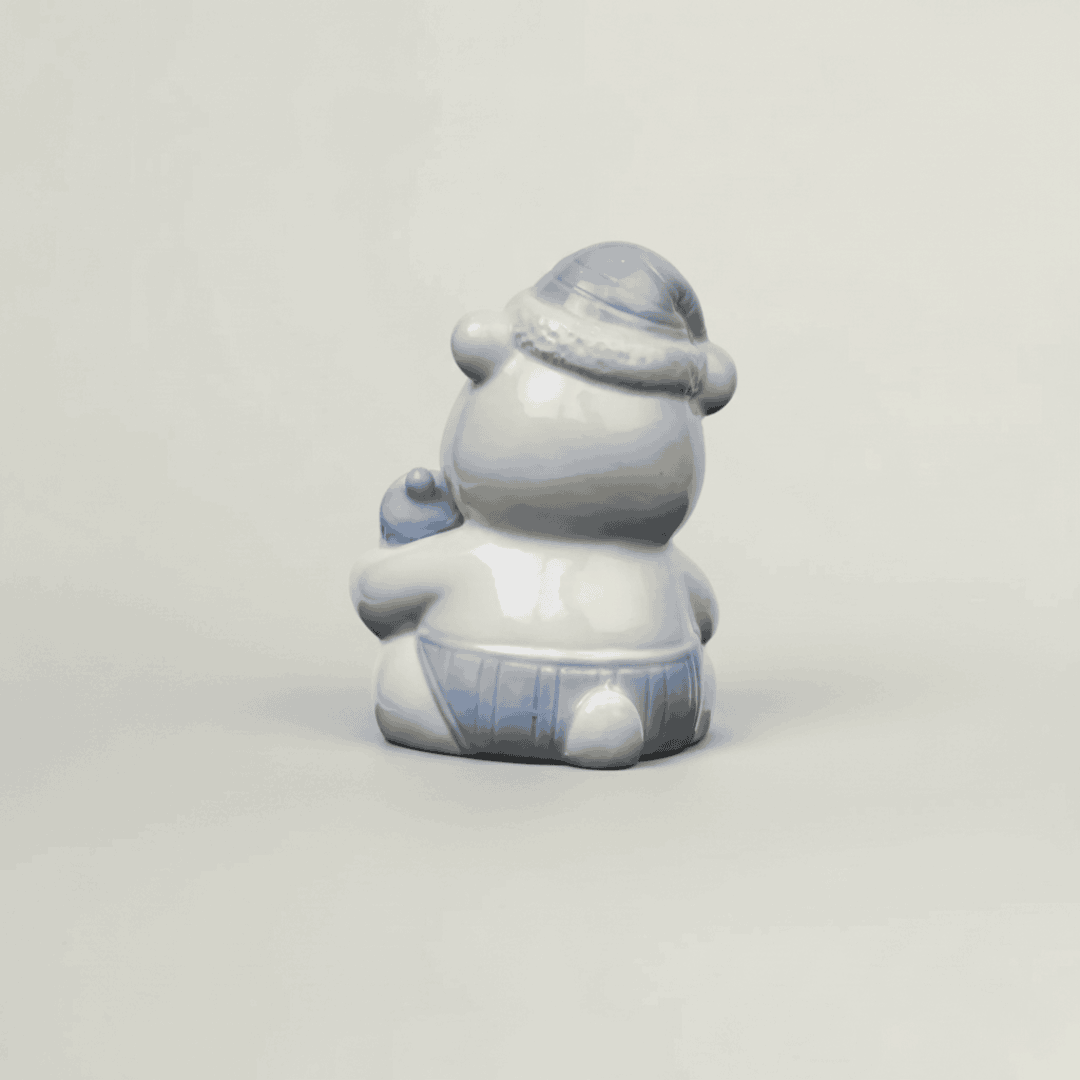 Back view of blue ceramic baby teddy bear figurine with glossy finish, pastel nursery shelf decor and baby keepsake collectible