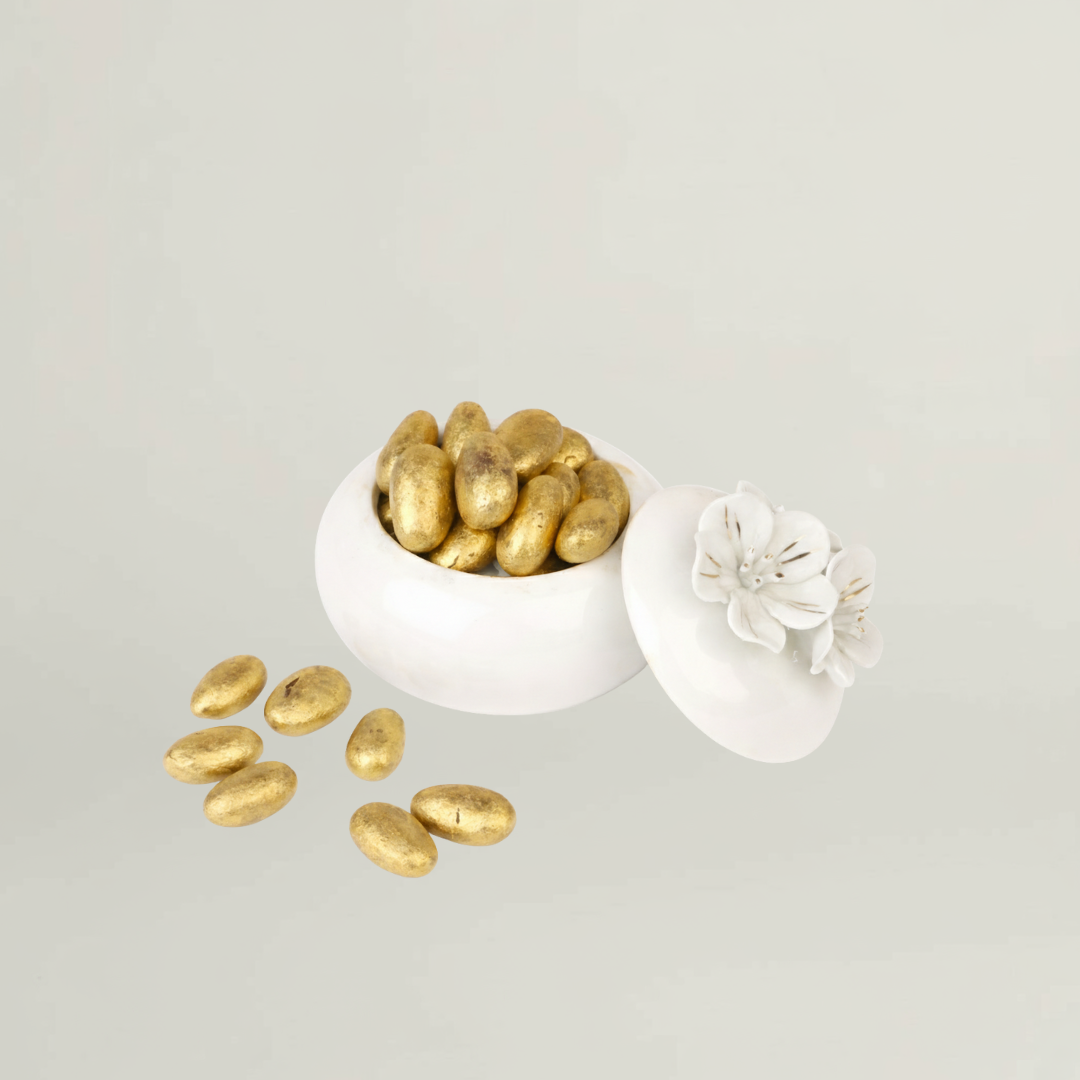 Floral ceramic jar filled with golden sugar coated almonds included in luxury baby gift hamper for newborn celebrations.