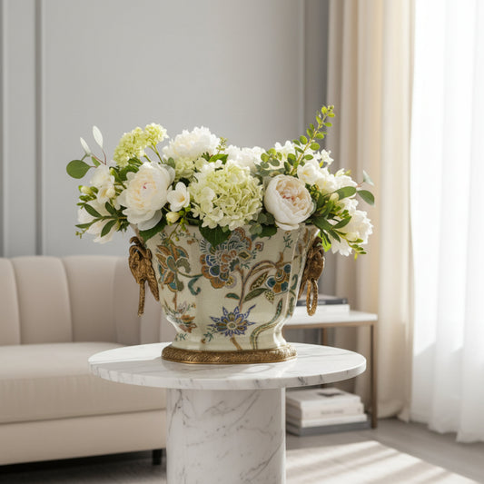 Cream ceramic floral planter with gold detailing, styled with fresh white flowers as a refined centerpiece for luxury interiors.