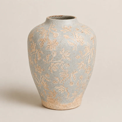 Handcrafted ceramic vase with embossed floral pattern in soft blue and beige tones.