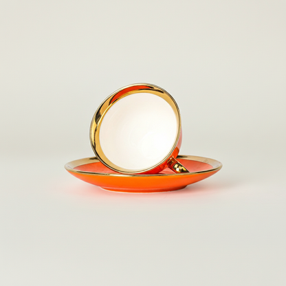 Orange tea cup placed upside down on matching saucer with gold detailing