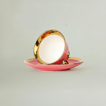 Pink tea cup displayed upside down on saucer with gold rim
