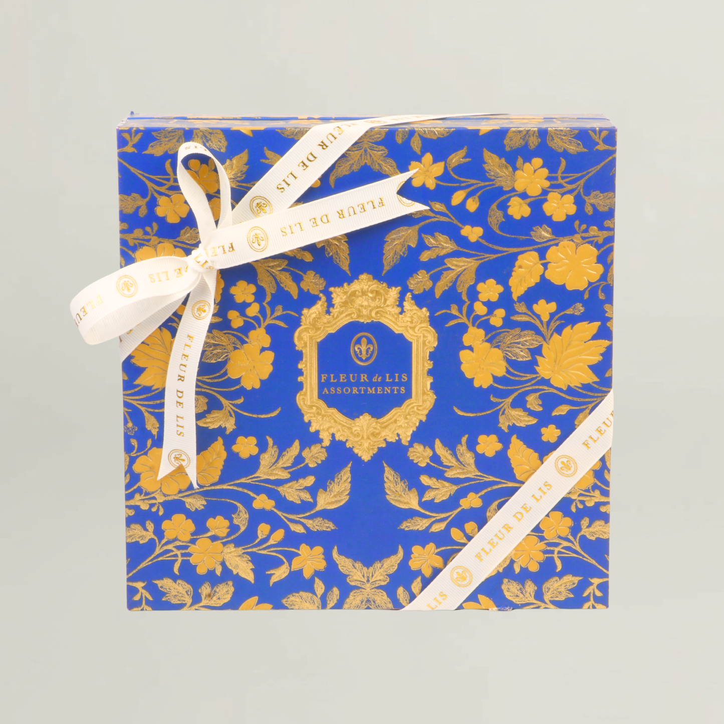 Royal blue and gold Fleur de Lis luxury hamper box with floral motifs and branded ribbon, designed for premium gifting occasions.