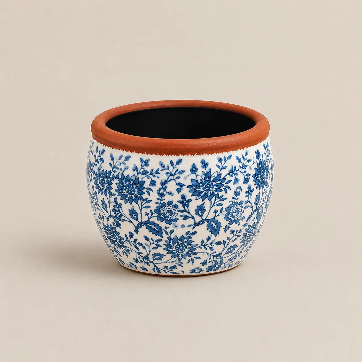 Small ceramic planter featuring hand-painted blue floral patterns and terracotta rim.