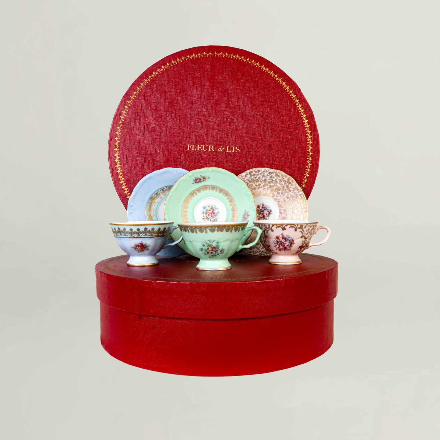 Assorted floral ceramic cups and saucers displayed in a round Fleur de Lis luxury presentation box.