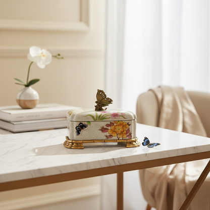 Luxury floral ceramic keepsake box with butterfly accent and gold base, styled on a marble console table for elegant home décor.