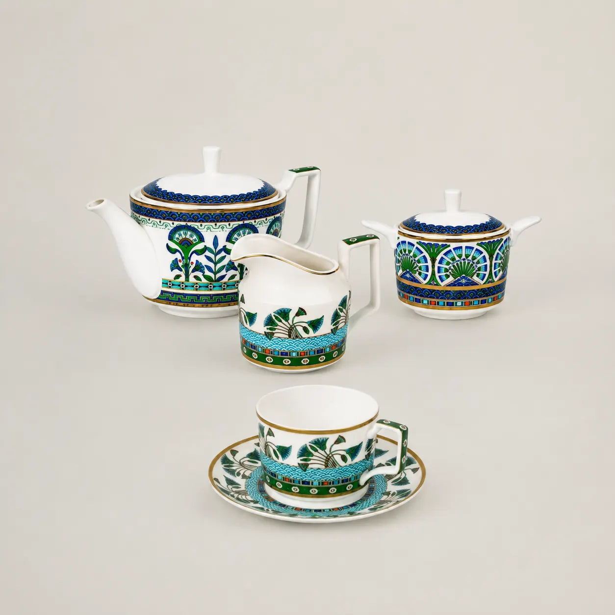 Elegant porcelain tea set with teapot, creamer, sugar bowl, and teacup featuring an intricate blue and gold pattern.