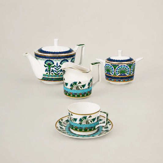 Elegant porcelain tea set with teapot, creamer, sugar bowl, and teacup featuring an intricate blue and gold pattern.
