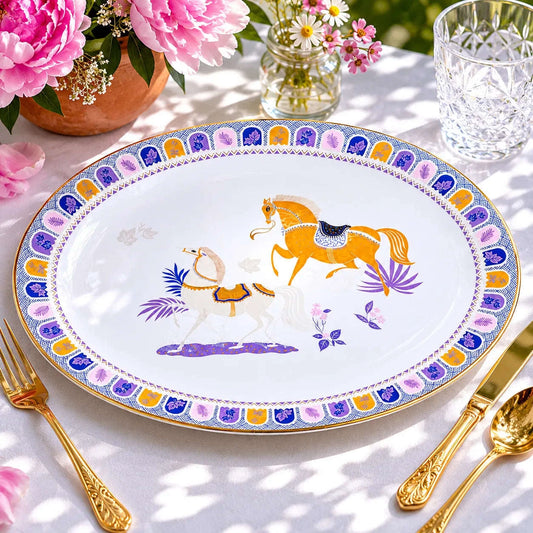 Equestrian serving platter styled with flowers and gold cutlery on a table.