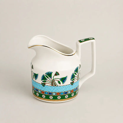 Elegant porcelain milk jug with floral motifs, gold rim and geometric handle.