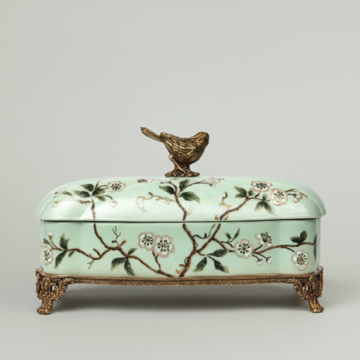 Mint green ceramic keepsake box with hand-painted floral branches, bird lid accent, and antique gold feet for elegant home décor.