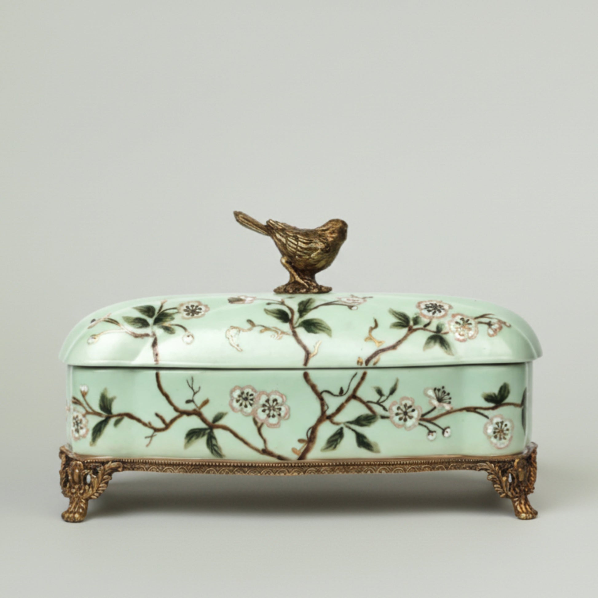 Mint green ceramic keepsake box with hand-painted floral branches, bird lid accent, and antique gold feet for elegant home décor.
