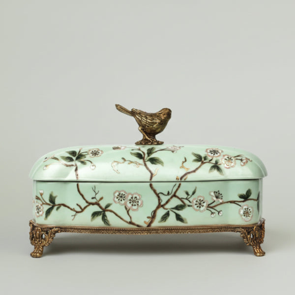 Mint green ceramic keepsake box with hand-painted floral branches, bird lid accent, and antique gold feet for elegant home décor.