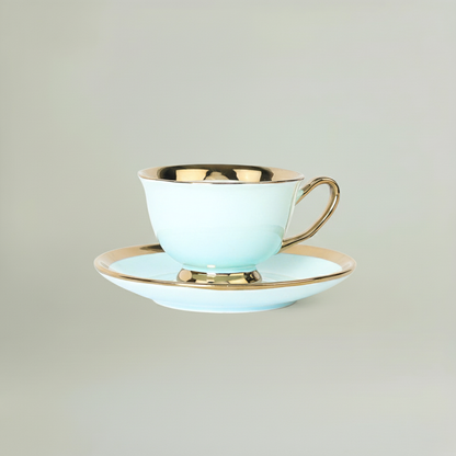 Sky blue ceramic coffee cup and saucer with elegant gold rim detailing, presented in a minimal studio setting.